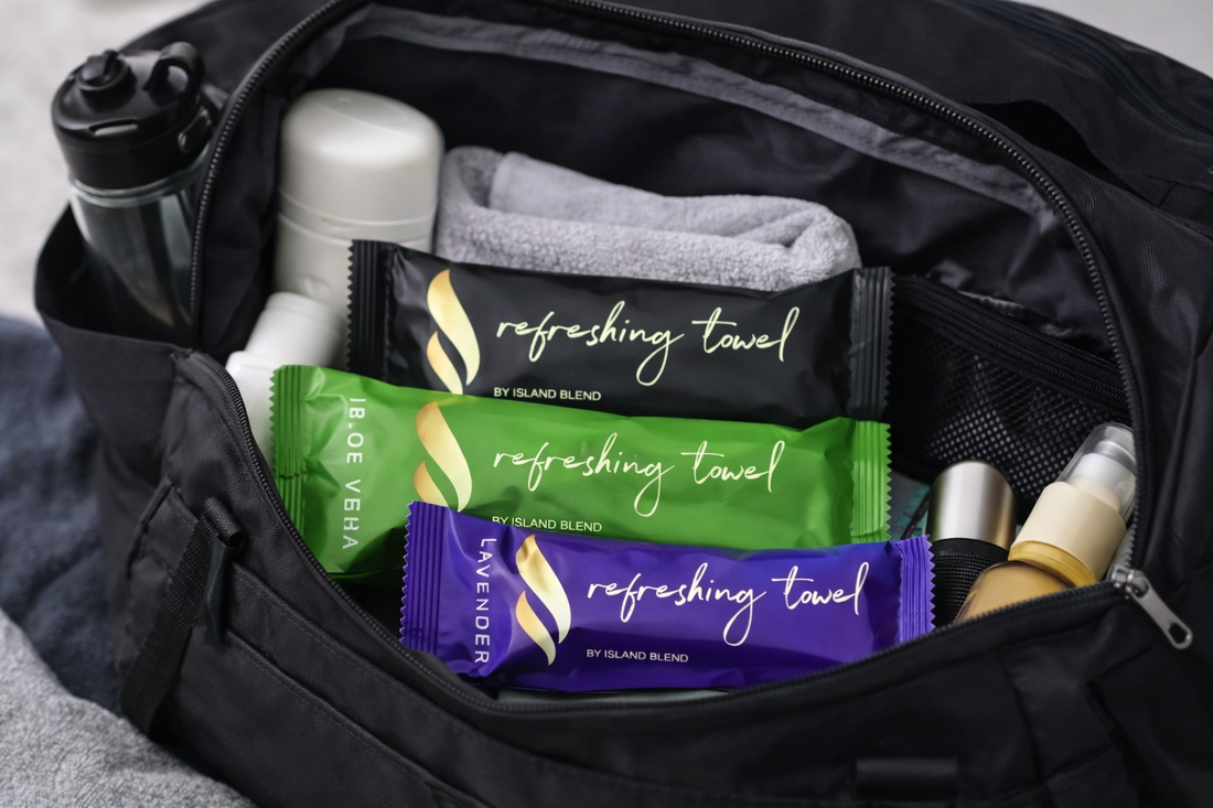 Refreshing towels in lavender, aloe vera, and black packaging placed inside an open gym bag with workout essentials.